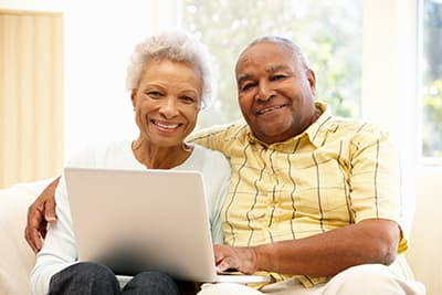 Older African American couple on couch with laptop.