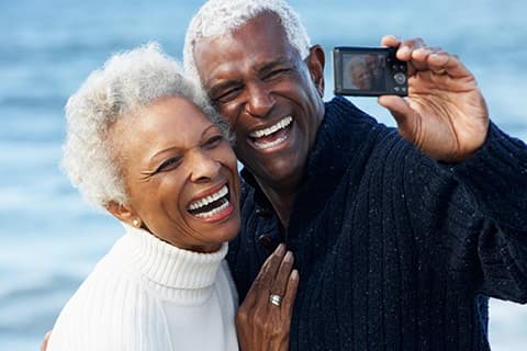 Senior couple with camera on beach